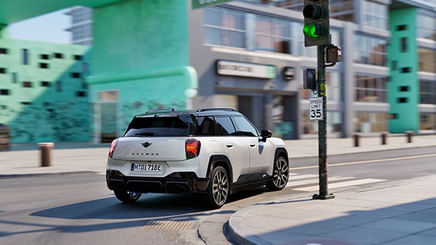 Ein MINI Aceman E fährt bei einer grünen Ampel um die Kurve